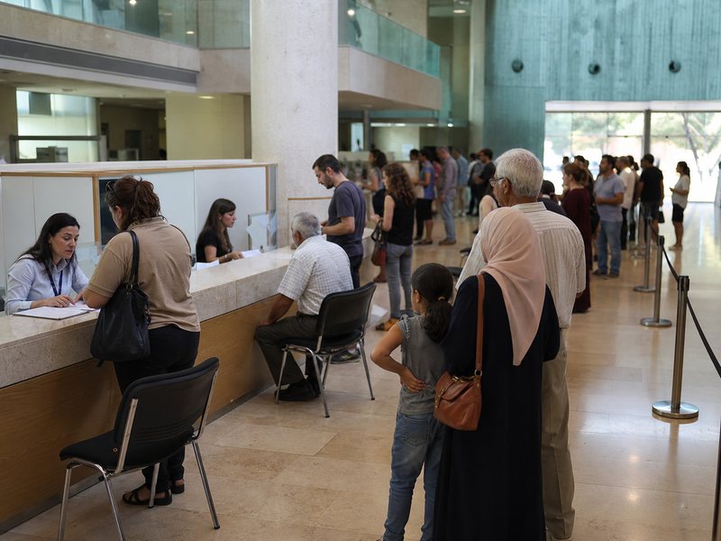 אנשים ממתינים ומקבלים שירות בדלפקים באולם ציבורי