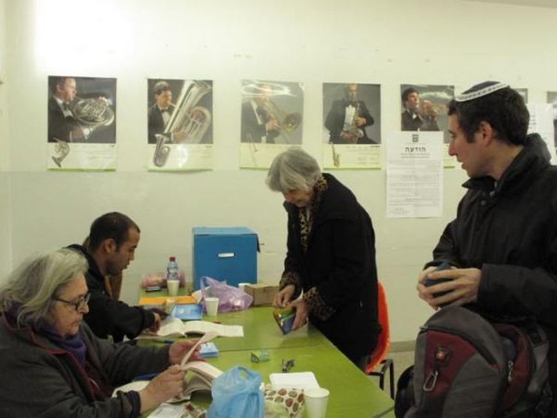 מצביעים וחברי ועדת קלפי סביב שולחן וקלפי כחולה בתחנת הצבעה בירושלים בבחירות 2009