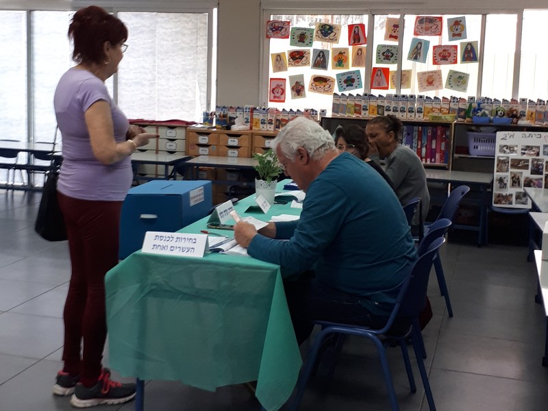 קלפי ביום הבחירות בישראל, ובה צוות יושב ליד שולחן ומקבל מצביעים