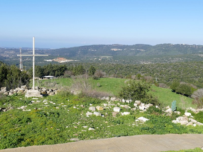 נוף ירוק ובו שרידי אבן וצלב, כמטפורה למקום, אובדן ועקירה פנימית מתמשכת