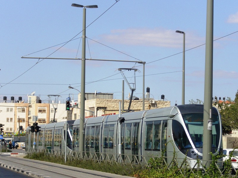 הרכבת הקלה נוסעת בשועפאט בדרום ירושלים בין כביש, עמודי תשתית ובתי מגורים