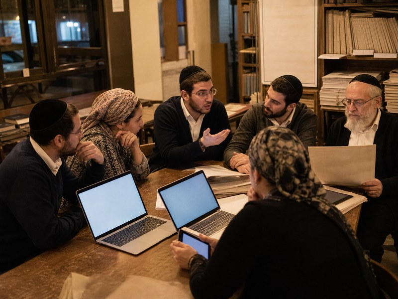 חברי קהילה שמרנית קוראים ומתווכחים סביב אתר חדשות דיגיטלי במרחב פנימי