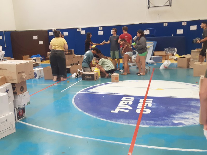 מתנדבים ממיינים ציוד ואורזים ארגזי סיוע באולם ספורט