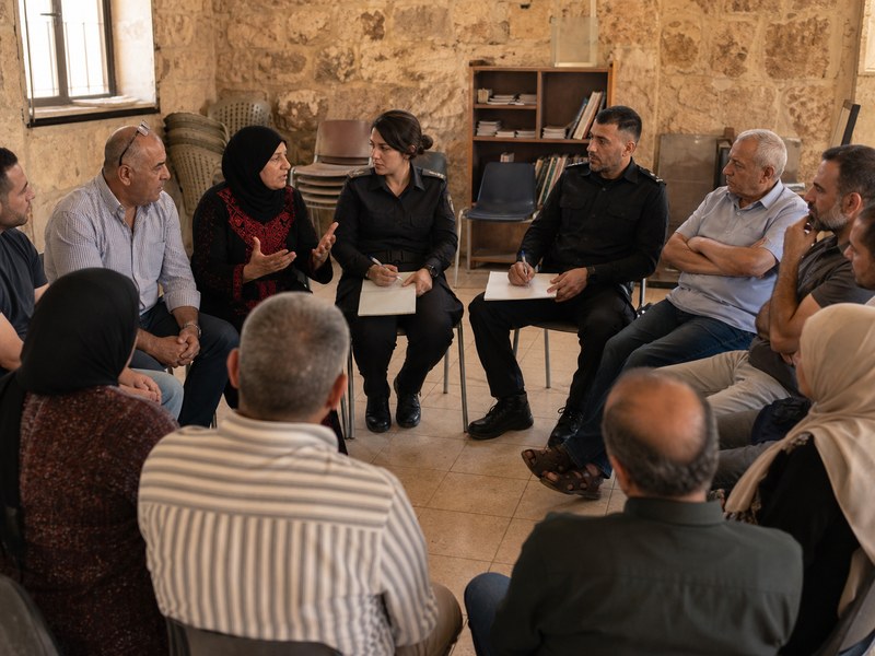 קבוצת תושבים מגוונת יושבת במעגל לשיחה על אמון ושוויון