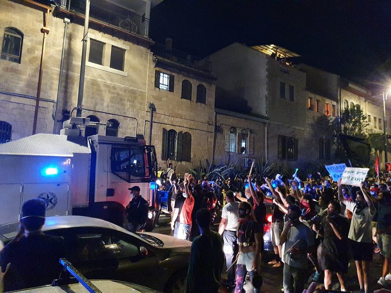 מפגינים מול מעון ראש הממשלה בירושלים בשעת ערב ביולי 2020, ולצדם רכב משטרתי
