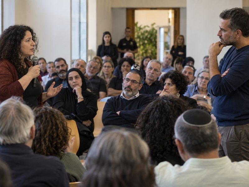 המחשה: אזרחים יהודים וערבים משתתפים בדיון ציבורי מתוח באולם קהילתי בישראל